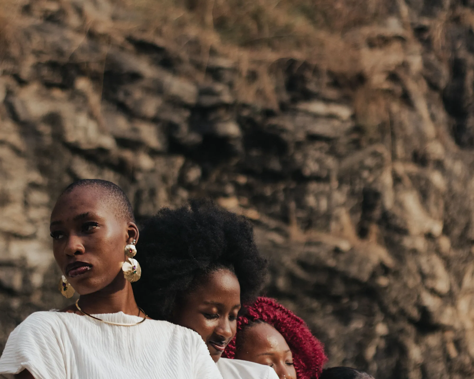 Un groupe de femmes réunies en plein air devant une paroi rocheuse, dans une lumière chaude.